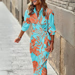 Woman wearing a blue and orange floral dress walking on a street.